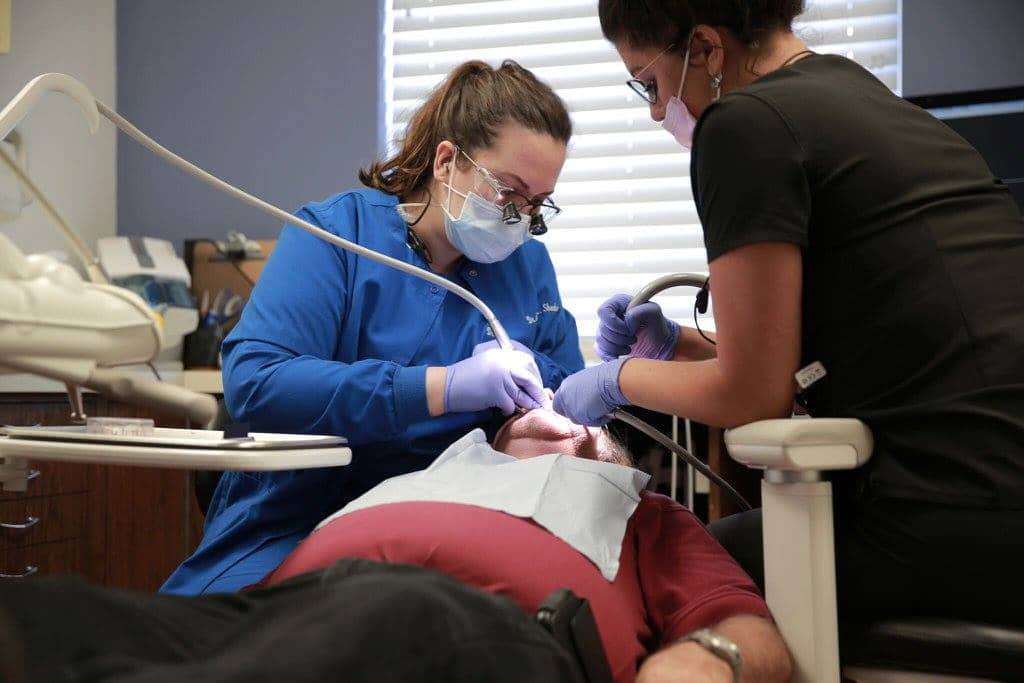 Dr. Sheehan and an assistant working on a patient's teeth as he lays back in the treatment chair