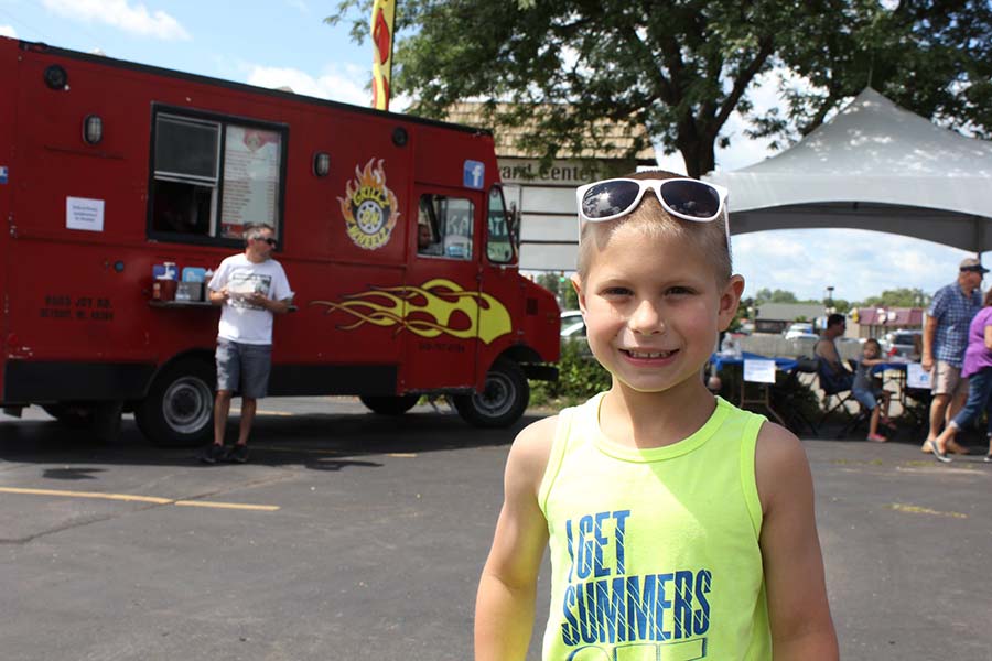 happy child wearing white sunglasses in front of food truck
