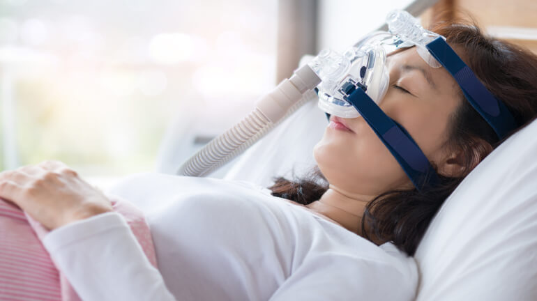 Woman wearing a cpap device while sleeping.