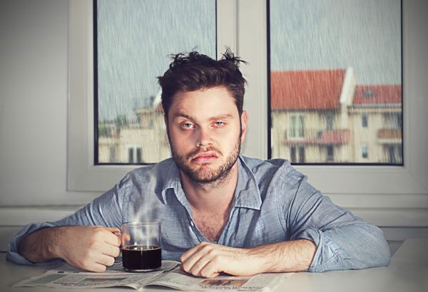 A man with his coffee looking very tired.
